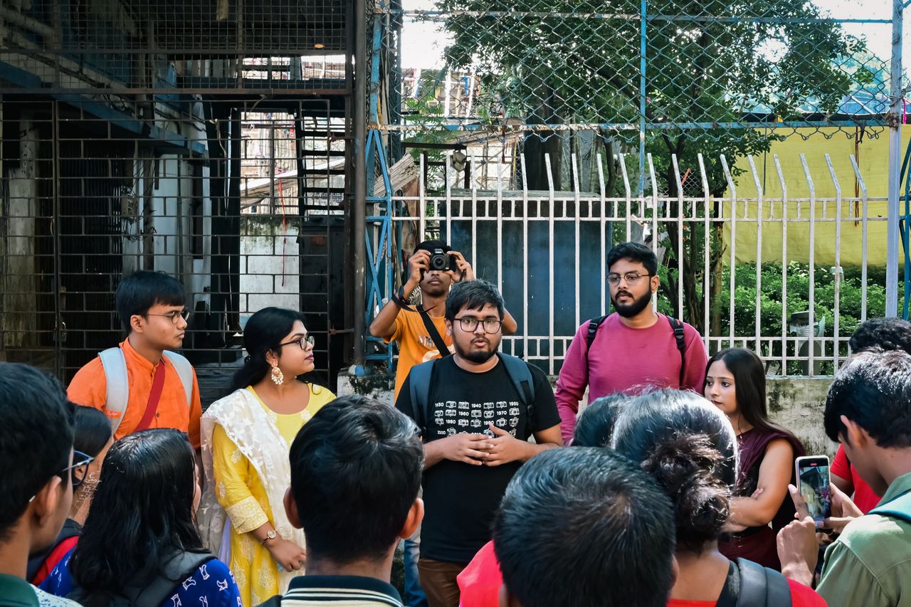 A diverse group of adults gathers for a photowalk in urban Kolkata, India.