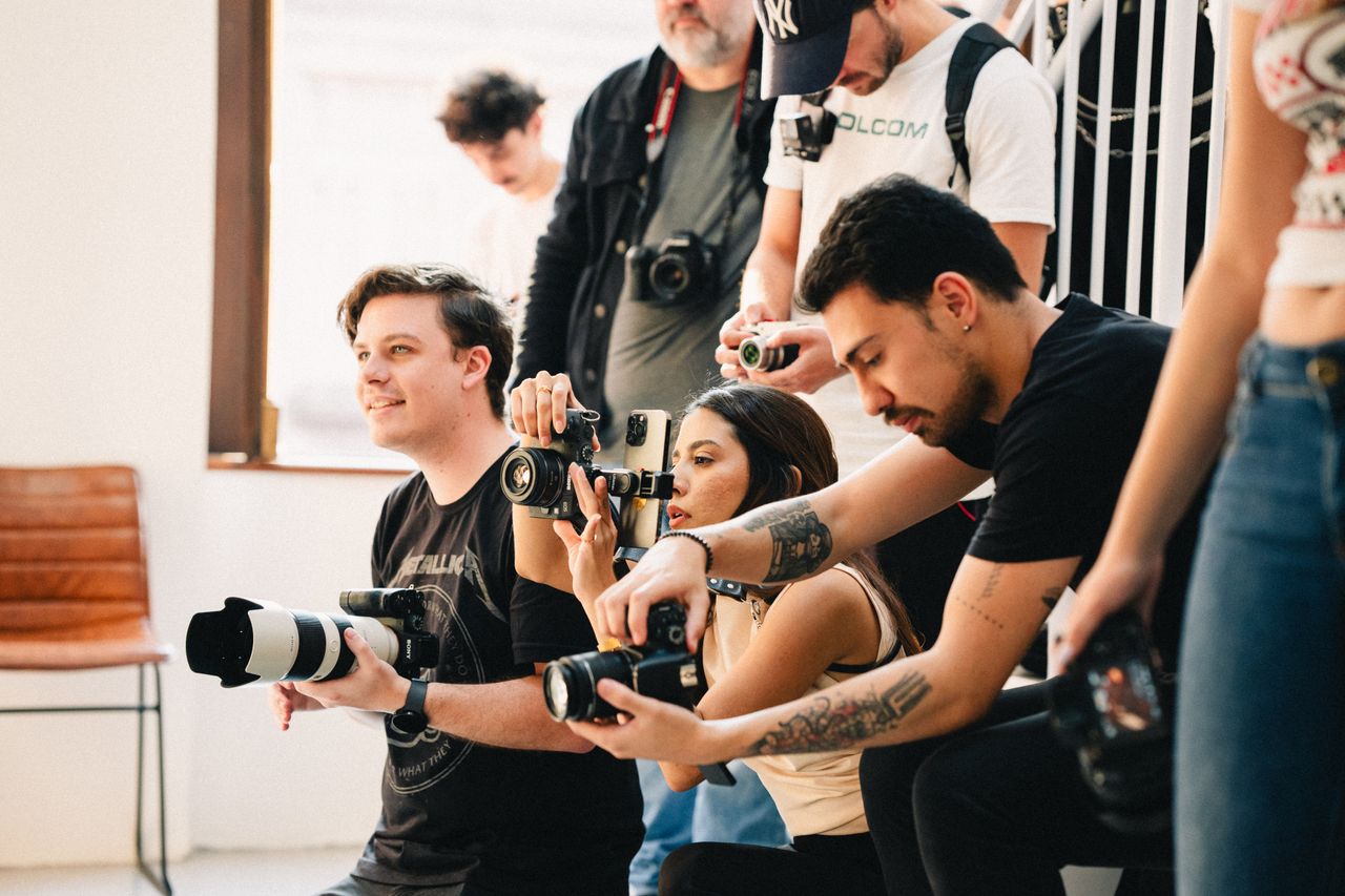 A group of photographers capturing moments with various cameras inside a studio setting.