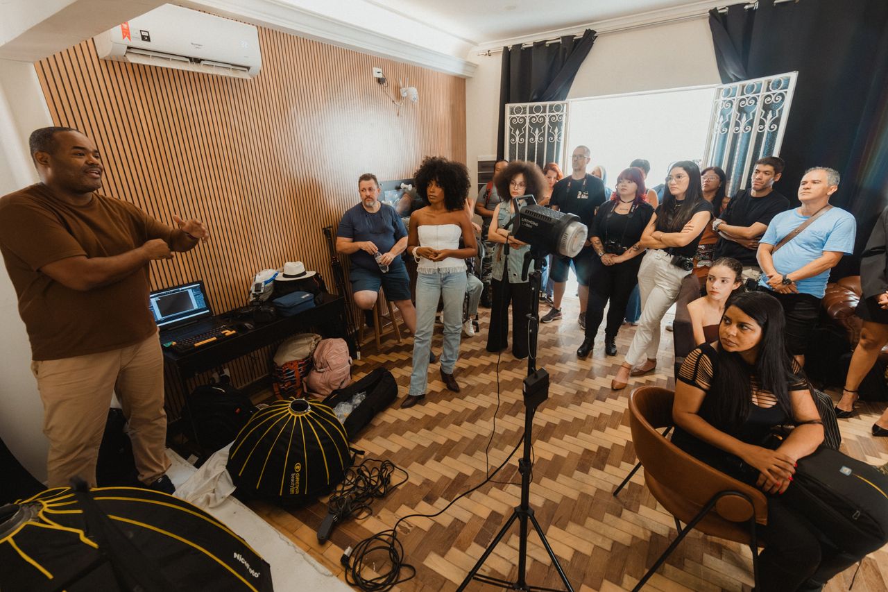 A group of adults attending a photography workshop indoors, featuring lighting equipment and informal setting.